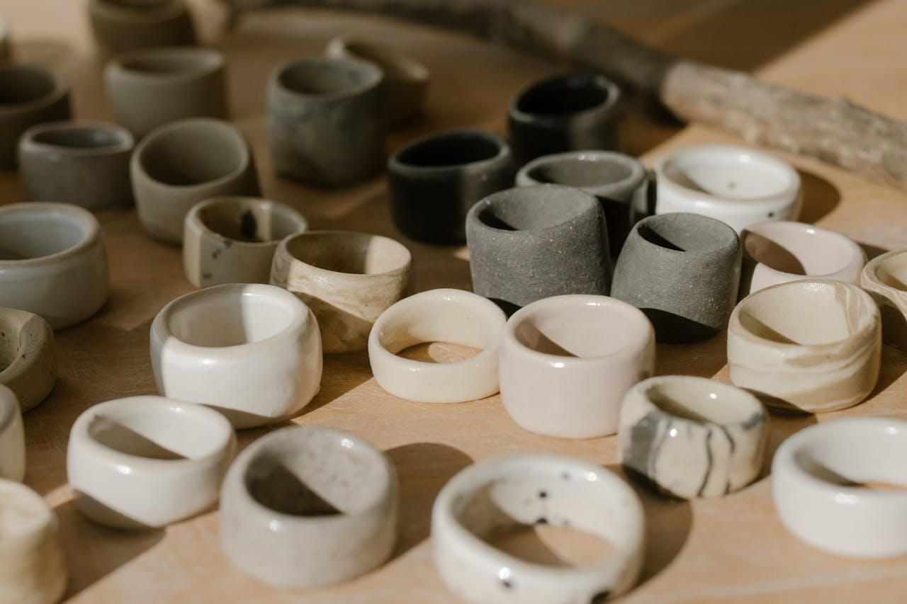 A collection of handmade ceramic rings showcased on a wooden surface with natural light.