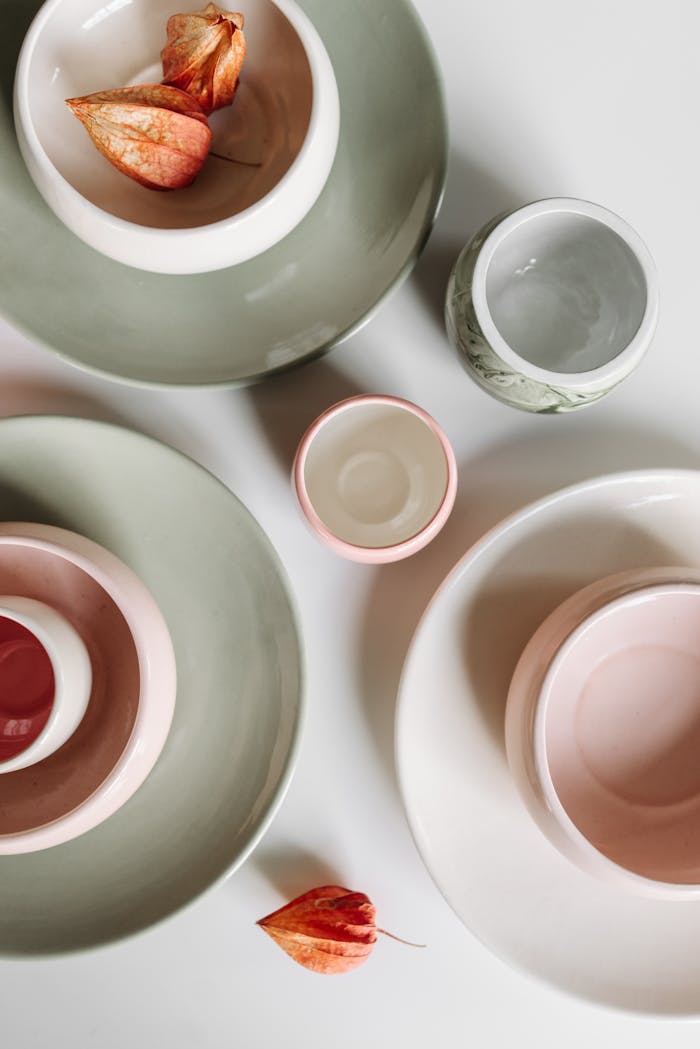Artistic flat lay of ceramic bowls and plates with organic design in pastel tones.